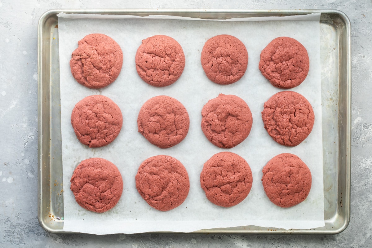 Baked red velvet cookies on a parchment paper lined baking sheet.