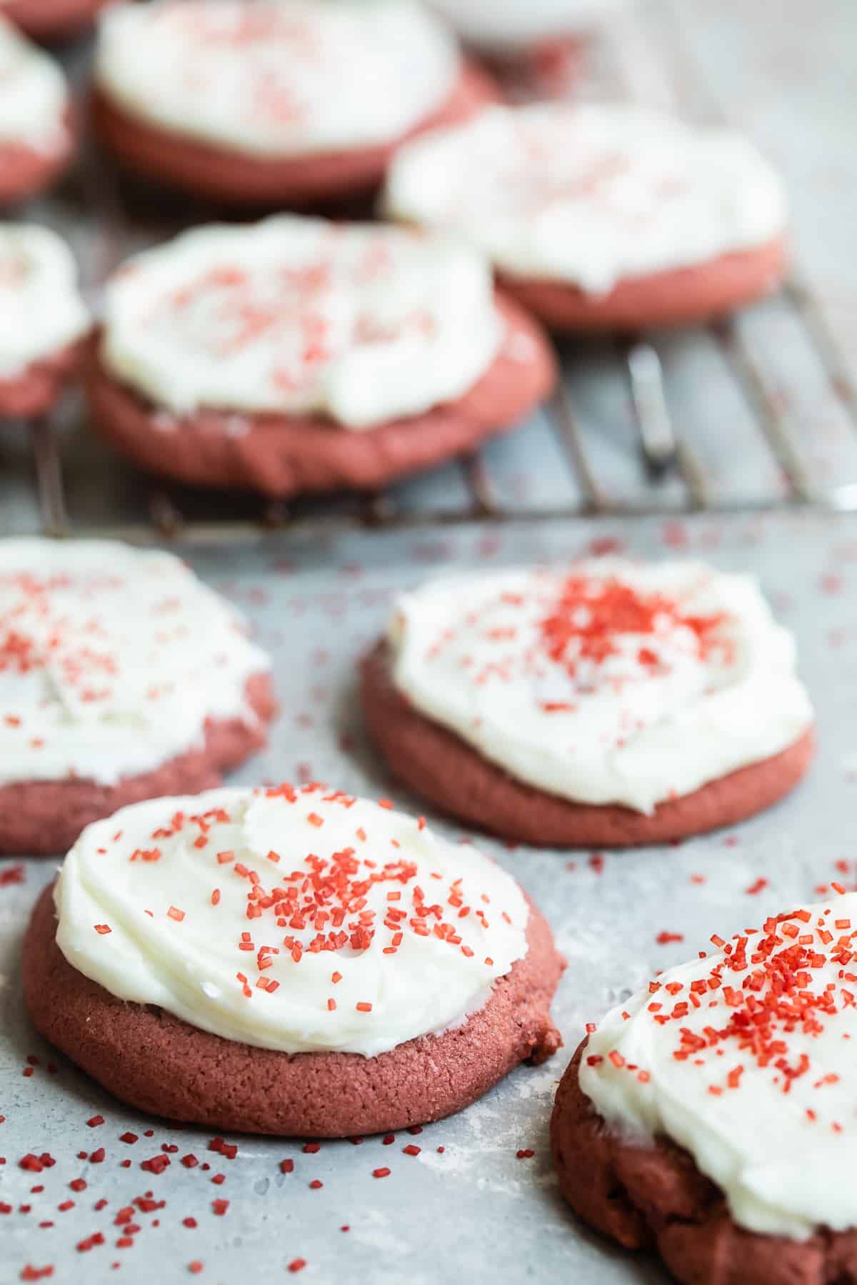 Red velvet cookies on a counter with a cooling rack behind them.