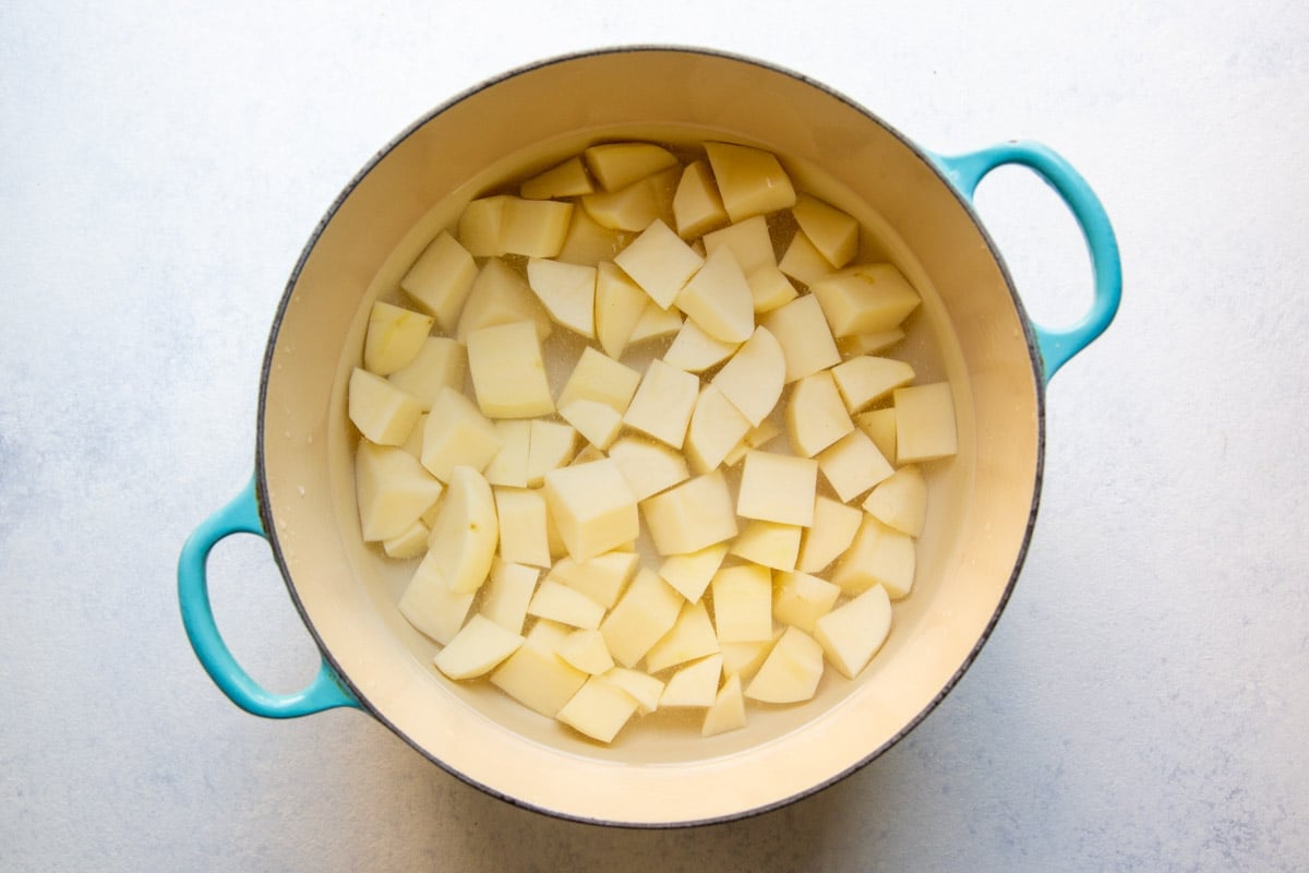 A Dutch oven with diced potatoes covered with water.