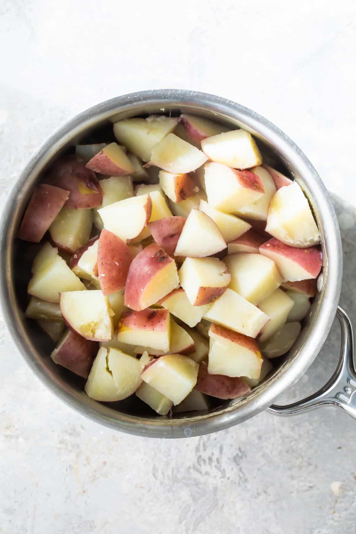 A saucepan full of peeled, diced red-skinned potatoes.