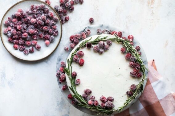 A cranberry wreath cake on a granite cake platter with a small plate of sugared cranberries next to it.