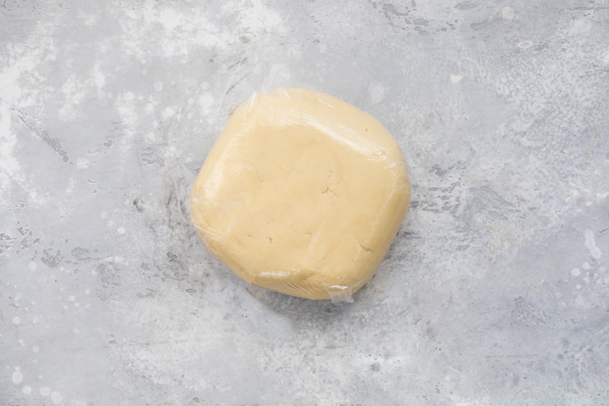 A disc of sugar cookie dough wrapped in plastic.