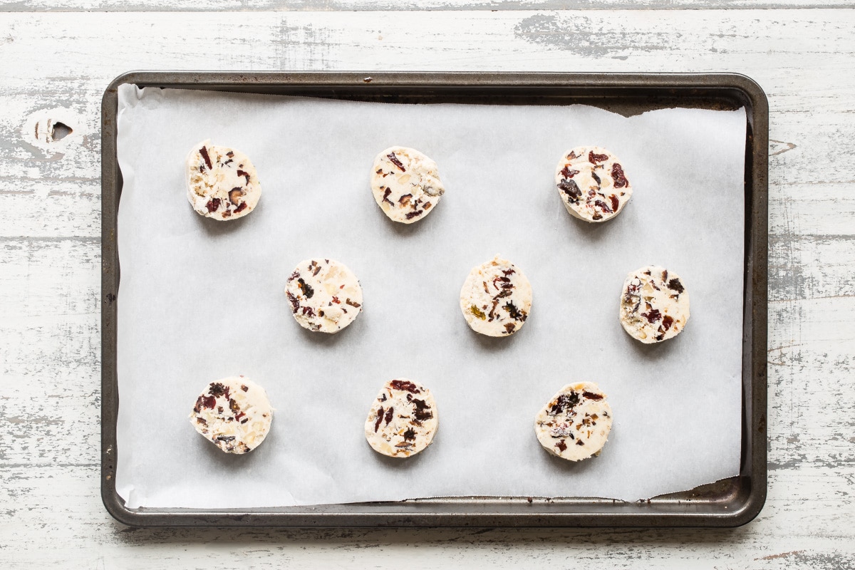Frozen cookie dough rounds on a parchment paper lined baking sheet.