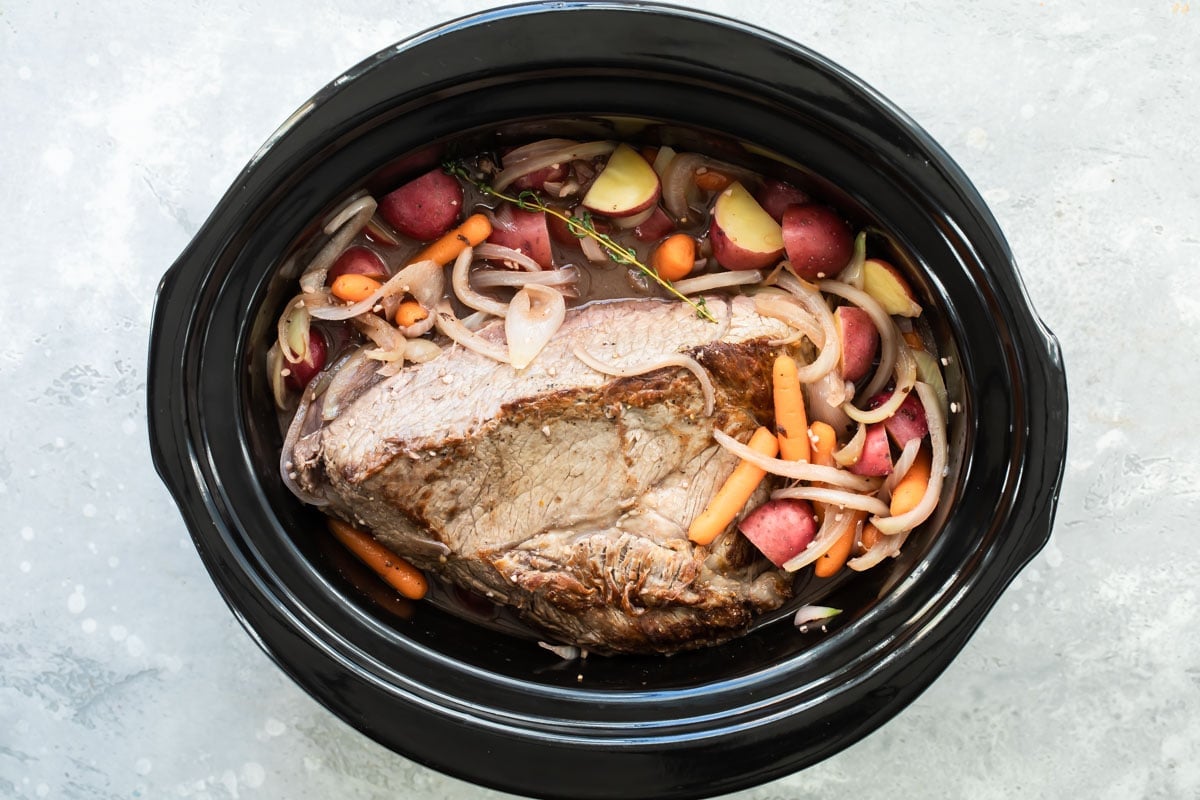 Cooked pot roast in a slow cooker.