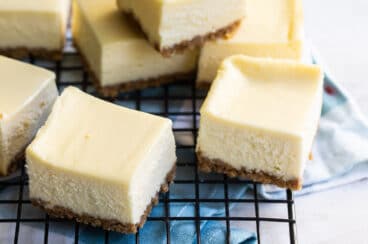 Cheesecake bars on a cooling rack.