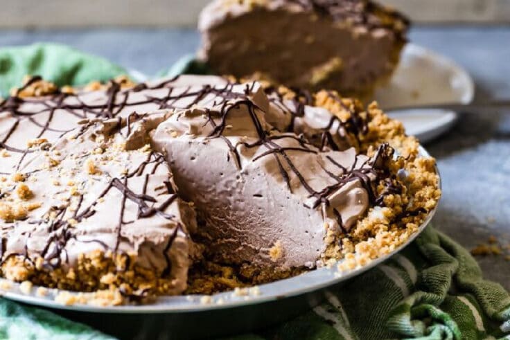 Chocolate cream pie in a pie dish with a slice in the background.
