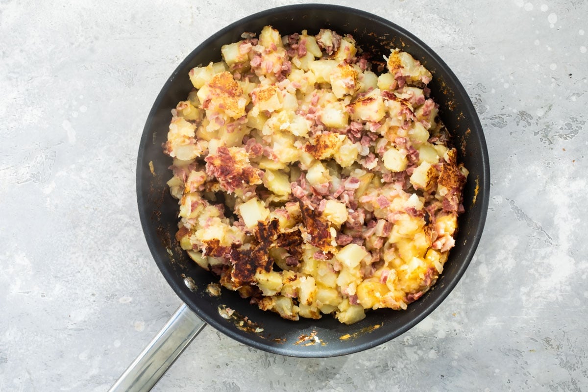 Corned beef hash cooking in a skillet.