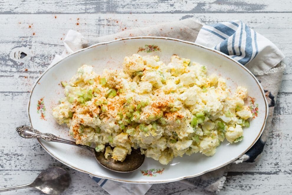 Potato salad in a white oval serving dish.