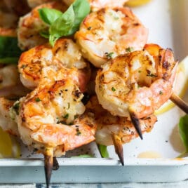 Grilled shrimp skewers in a white tray.