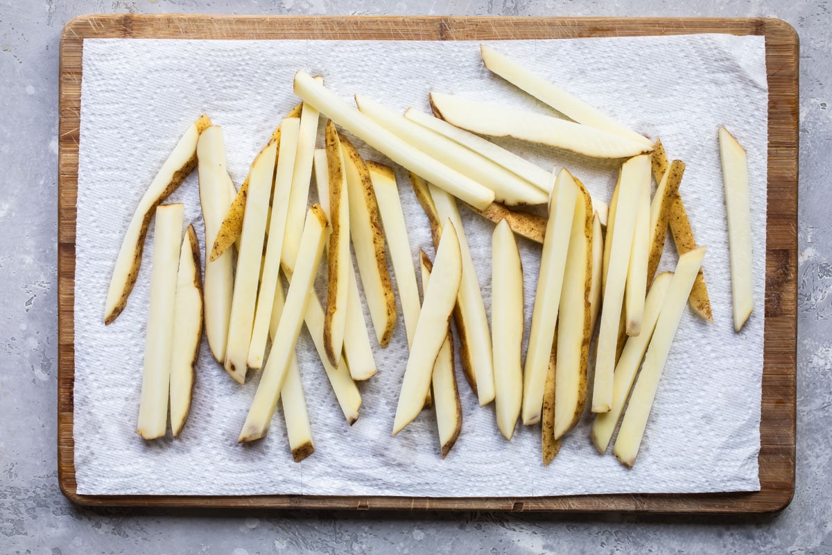 Raw French fries draining on paper towels.