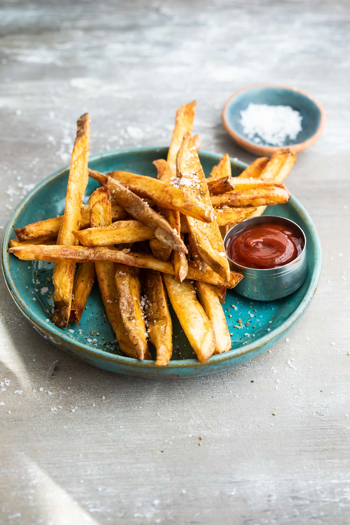 Homemade French fries on a teal plate with ketchup.