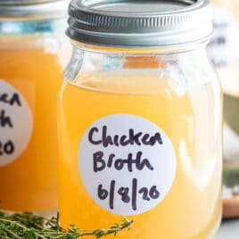 Homemade chicken broth in a jar on a plate.