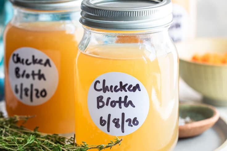 Homemade chicken broth in a jar on a plate.