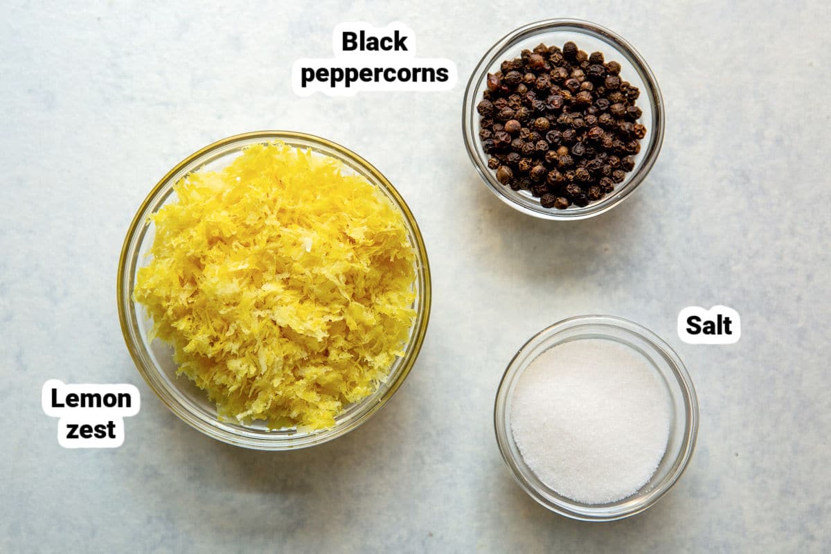 Bowls of lemon zest, black peppercorns, and salt for making lemon pepper seasoning.