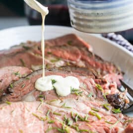 Mustard cream sauce being drizzled over a prime rib.