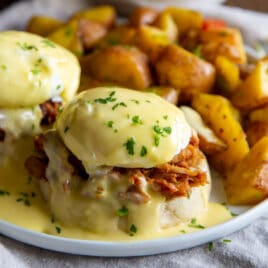 Pulled pork eggs benedict with a side of breakfast potatoes.