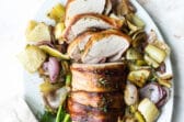 Bacon wrapped pork tenderloin surrounded by roasted fennel and onions.