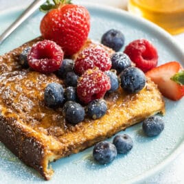 Baked french toast on a plate covered with berries.
