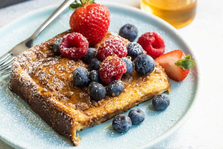 Baked french toast on a plate covered with berries.
