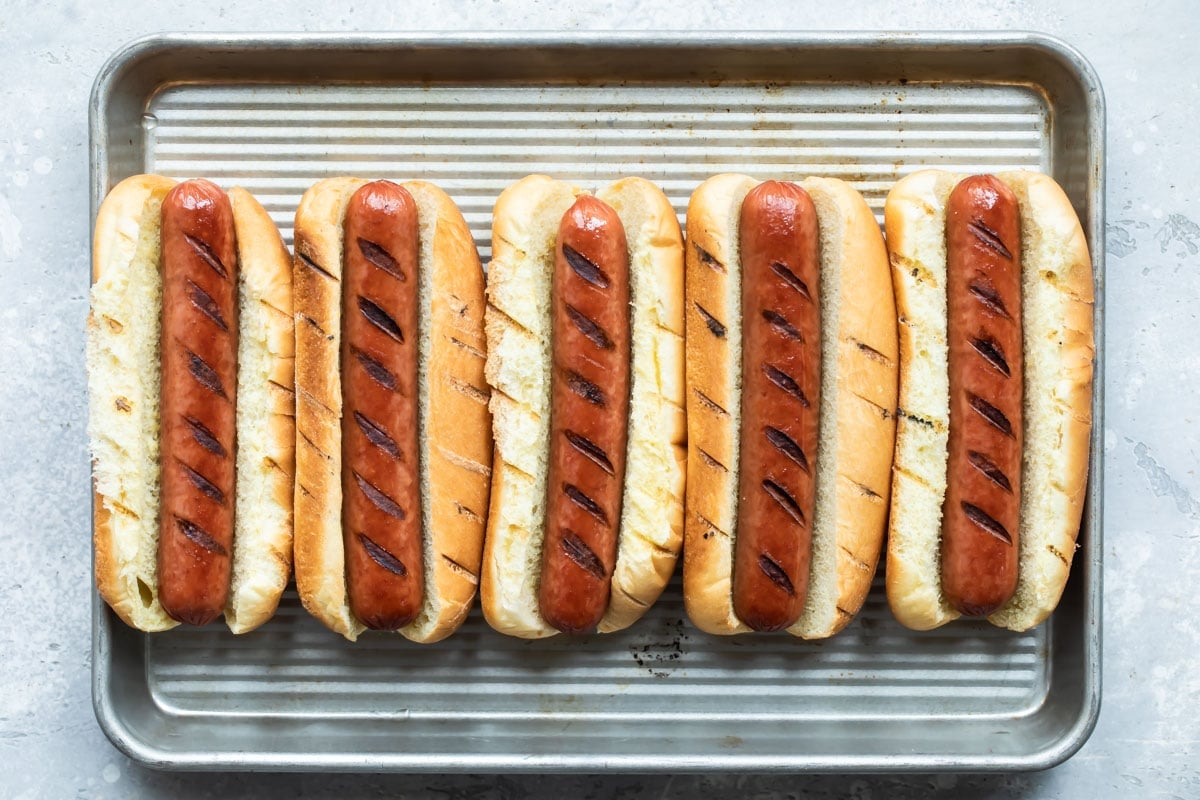A tray of grilled hot dogs in buns.