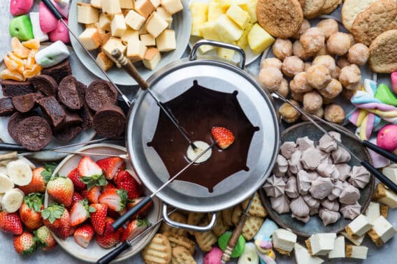 A platter of chocolate fondue and colorful dippers like fruit and sweets.