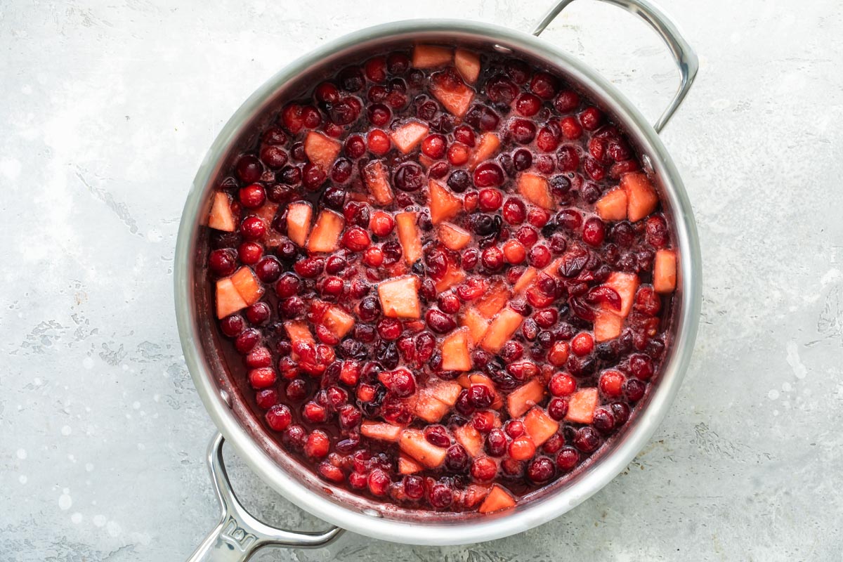 Cranberries and apples cooking in a saucepan.