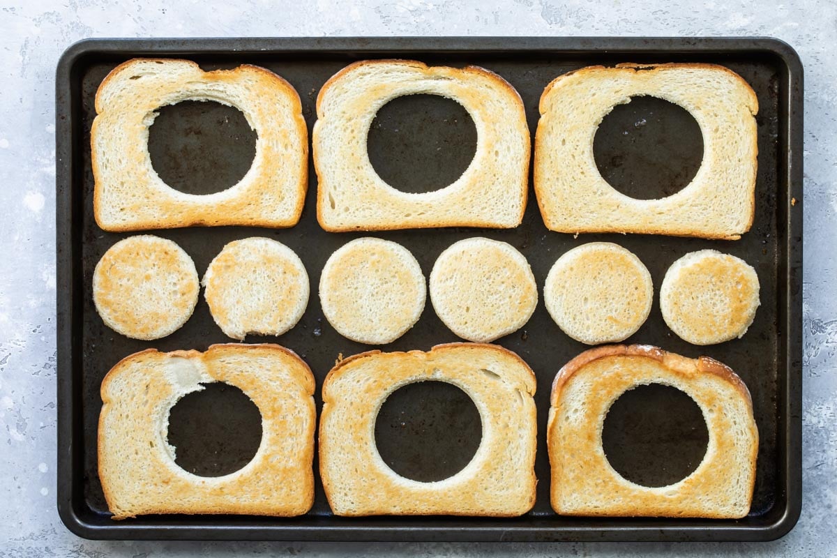 Eggs in a basket cooking on a sheet pan.