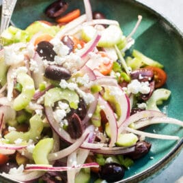 Greek salad in a teal bowl.