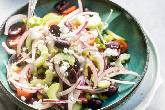 Greek salad in a teal bowl.