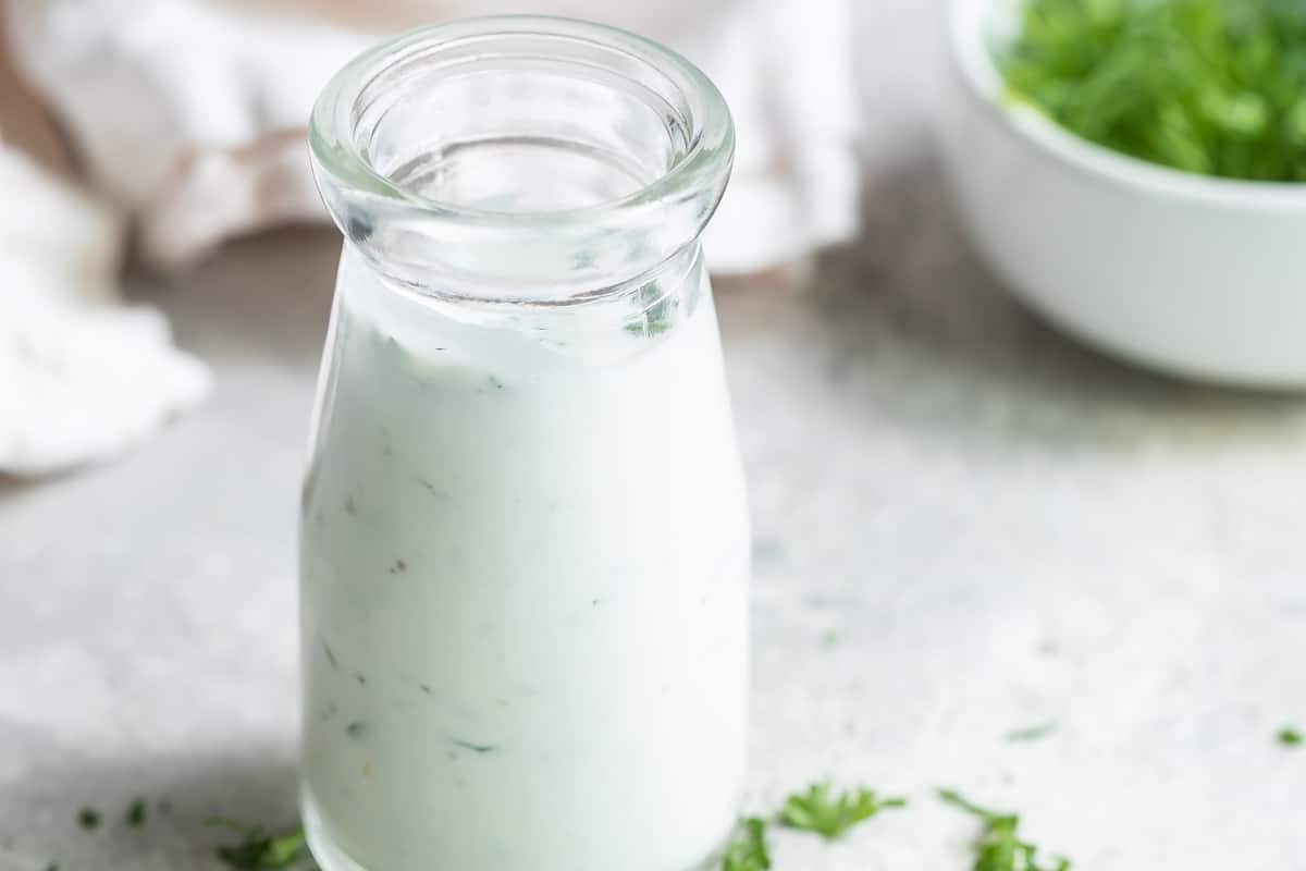 Homemade Ranch dressing in a clear glass bottle.