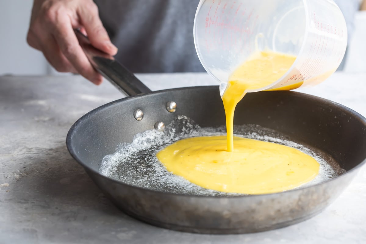 Scrambled eggs being poured into a pan.