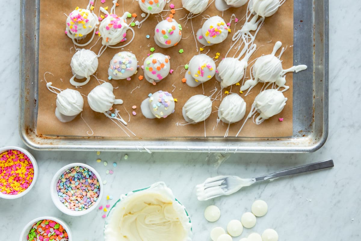 Lemon cookie balls decorated with white melting wafers on a baking sheet.