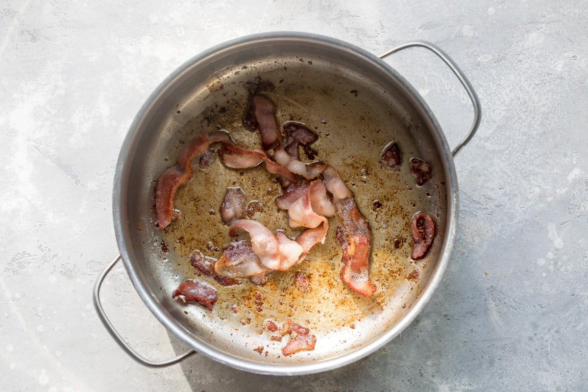 Bacon cooking in a silver pot.
