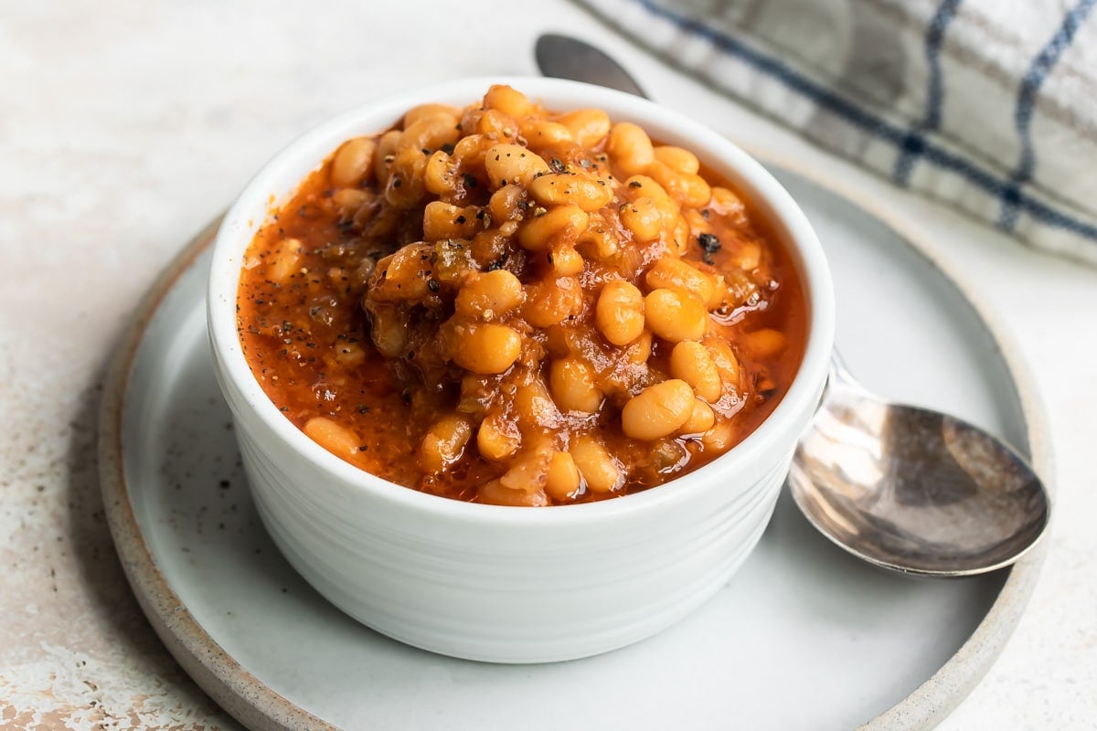 Slow cooker baked beans in a small white bowl.