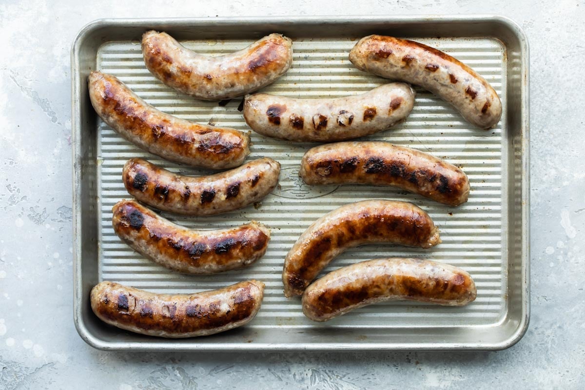 Grilled beer brats resting on a baking tray.