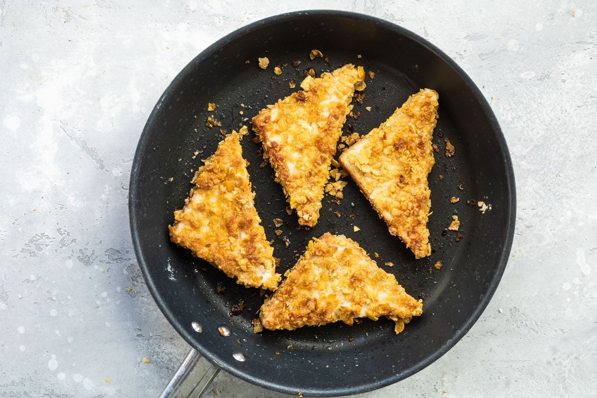Cornflake crusted French toast frying in a skillet.