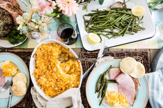 A table set for Easter with baked ham, scalloped potatoes, roasted green beans, and homemade biscuits.
