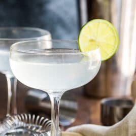 Gimlets in stemmed glasses with lime slices.