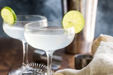 Gimlets in stemmed glasses with lime slices.