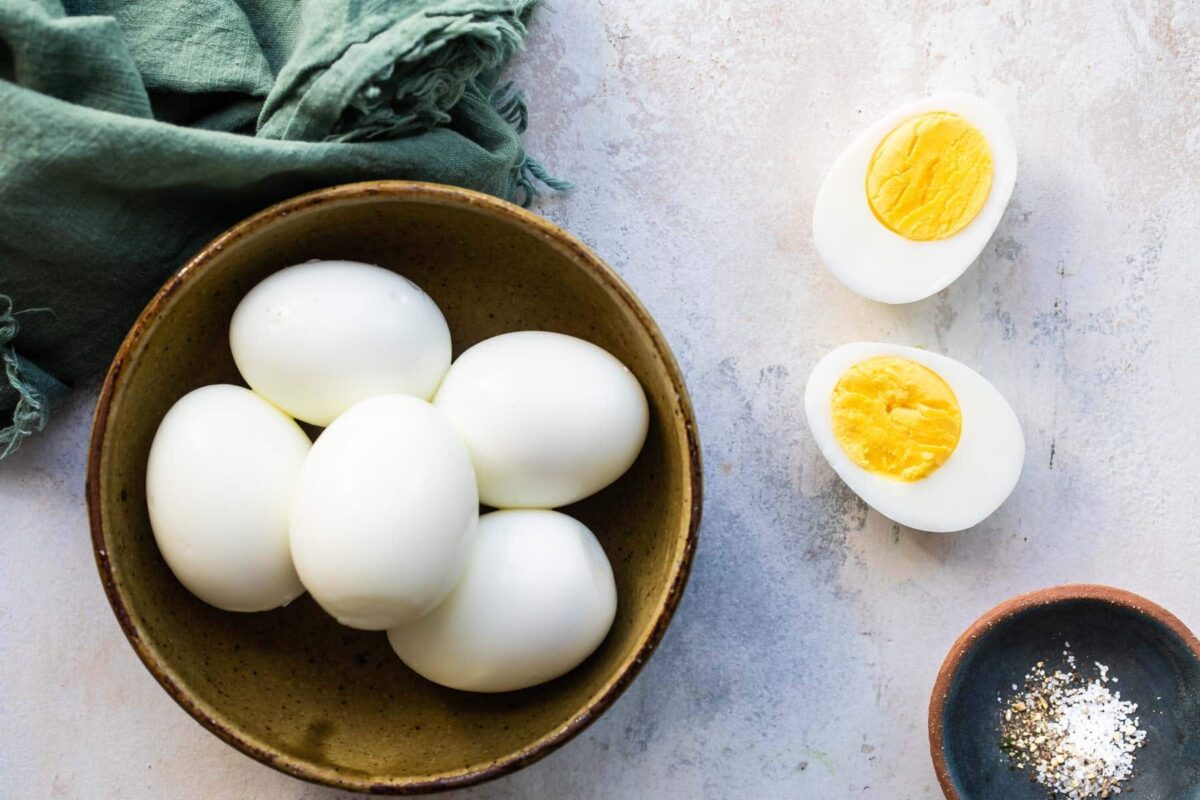 Hard-boiled eggs in a bowl, one split in half in front.