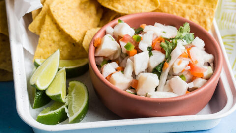 Taliapa ceviche in a pink bowl on a white platter with tortilla chips.