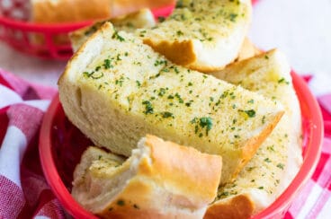 Garlic bread in a plastic red basket.