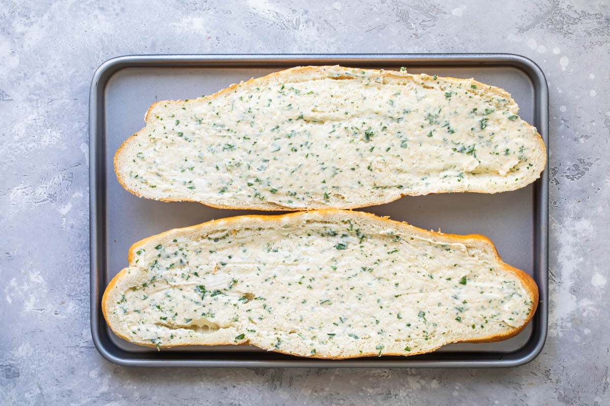 Uncooked garlic bread on a baking sheet.