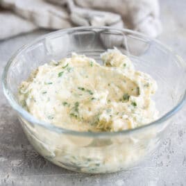 A clear bowl with some garlic spread in it.