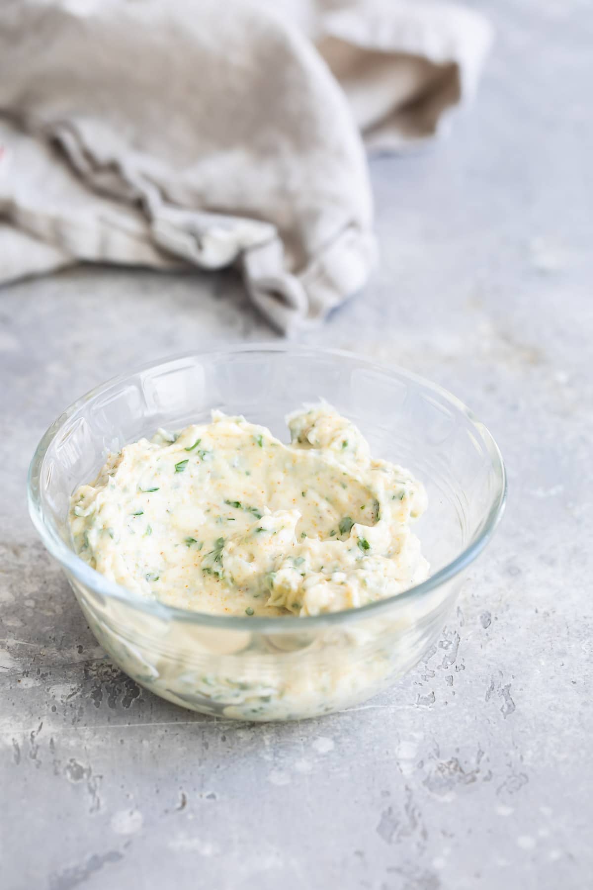 A clear bowl with some garlic spread in it.