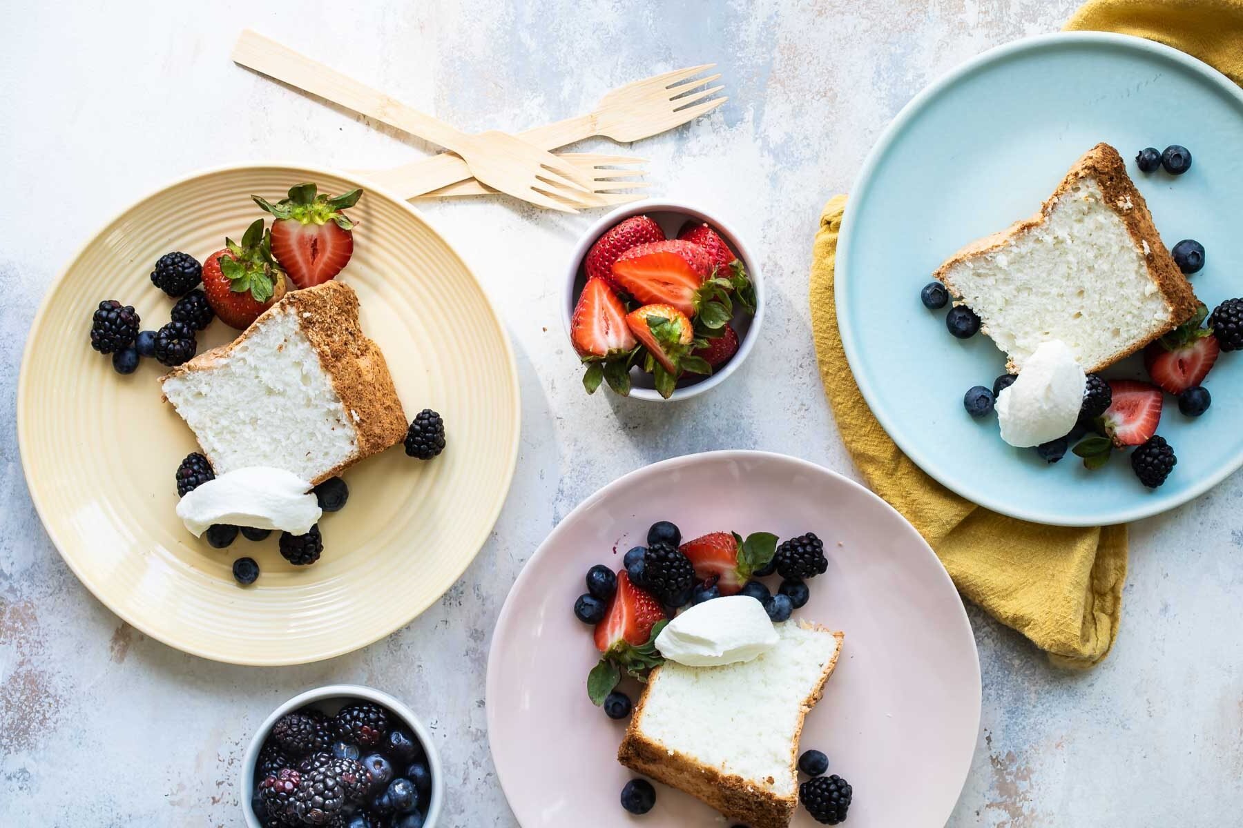 Slices of angel food cake with fresh berries and whipped cream.
