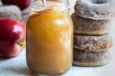 Brandy apple cider slush in a mason jar next to a stack of four brown donuts.