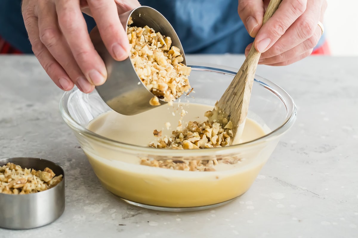 Pouring walnuts into a bourbon pie filling.