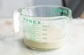 A glass measuring cup with yeast activating in warm water.