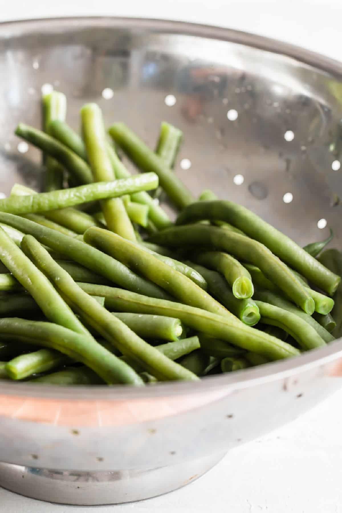 Green beans in a sliver colander.